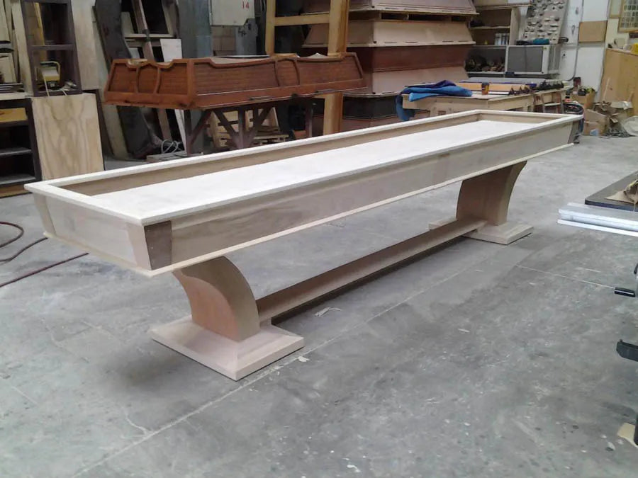 A long custom shuffleboard table in light wood on the CB Design workshop floor