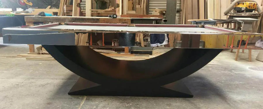 A custom pool table with a black curved cradle base and white top under construction