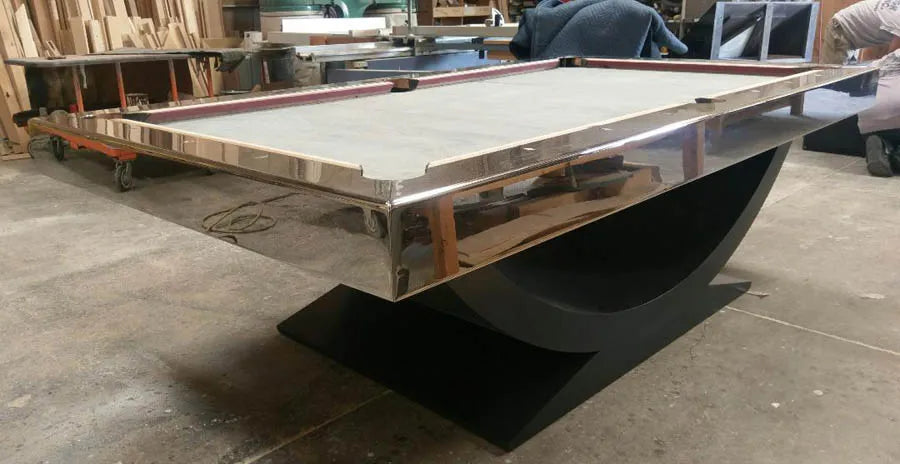 A custom pool table with a polished chrome cradle base being built in the workshop