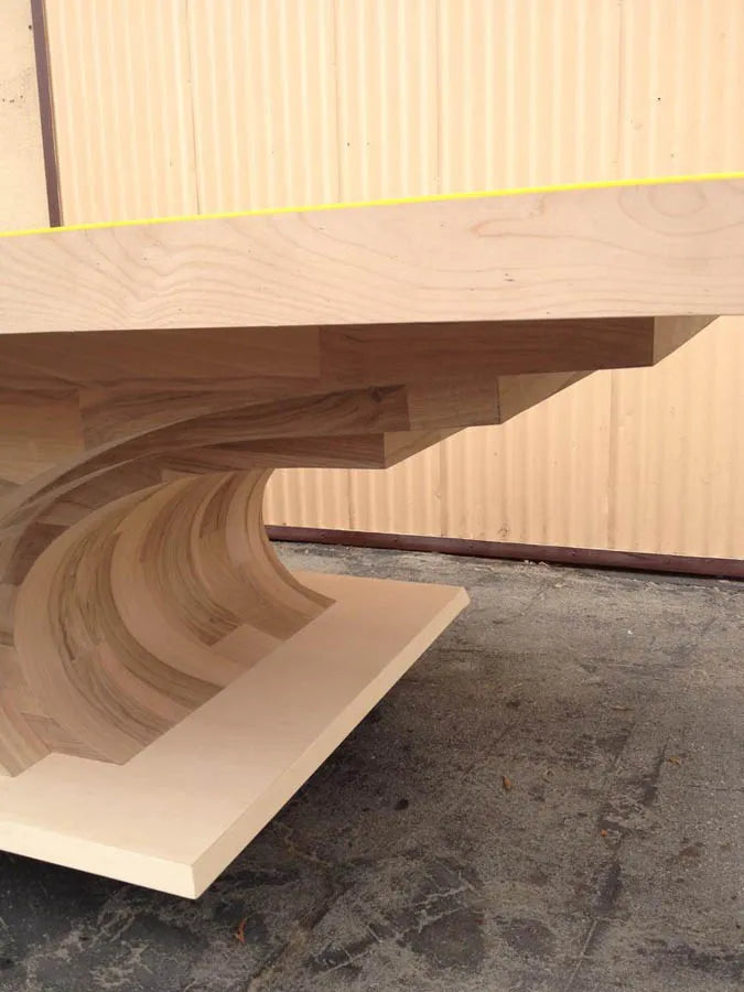 Close-up of a hand-shaped curved hardwood table base before finishing