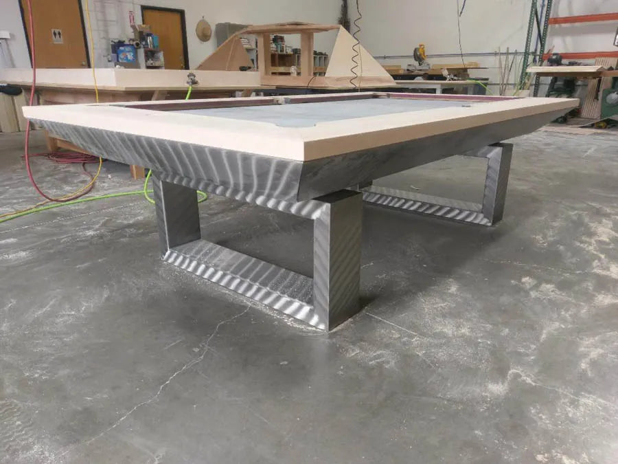 A cantilever pool table with a brushed metal base under construction