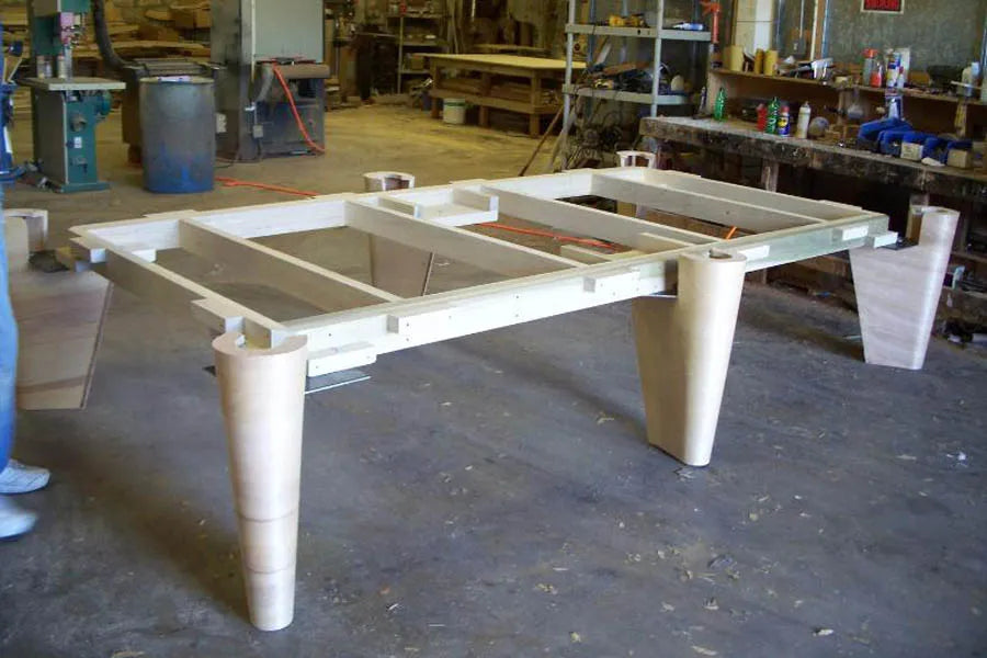 A custom table frame with turned legs being assembled in the workshop