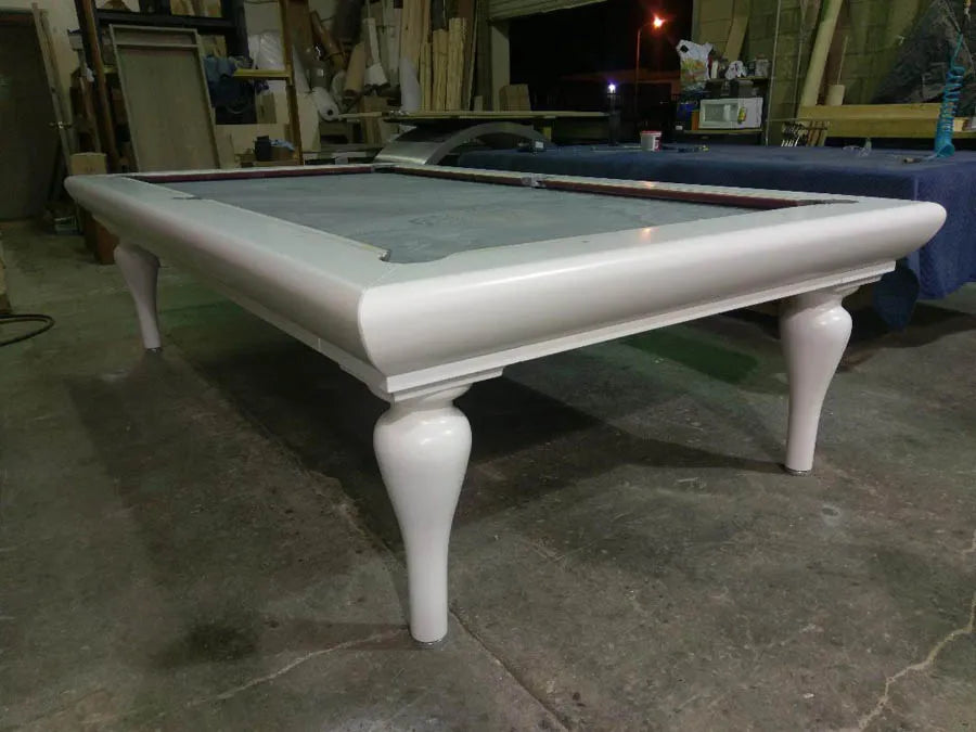 A custom pool table with turned legs and green cloth nearing completion