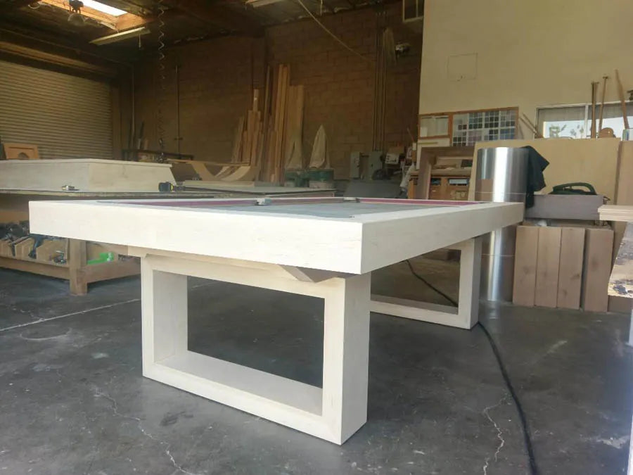 A white modern pool table with an open pedestal frame under construction