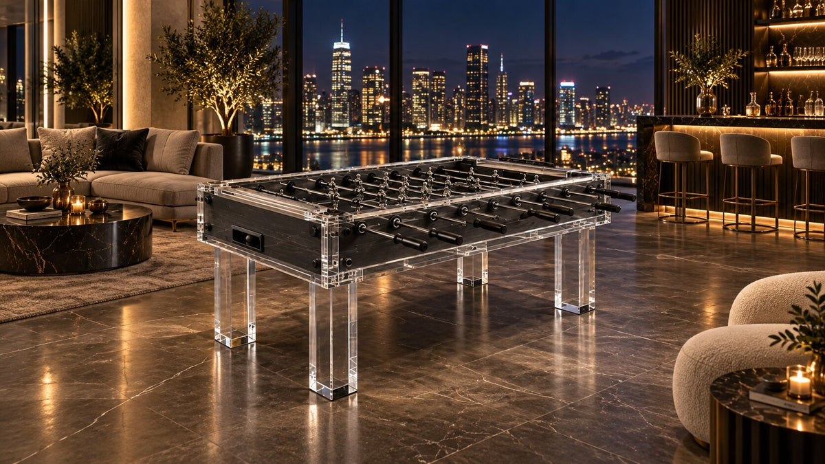 A lucite foosball table in a moody evening lounge with blue seating and city lights