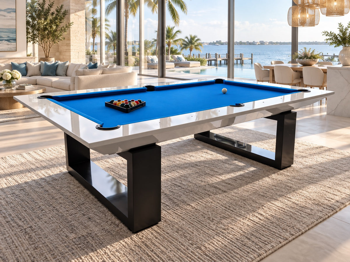 White and black modern pool table with blue cloth in a bright waterfront room